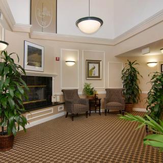 A cozy lobby area with comfortable chairs, a fireplace, and lush plants.