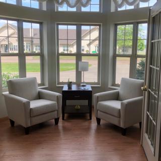 A cozy seating area with two armchairs and a small table by large windows.