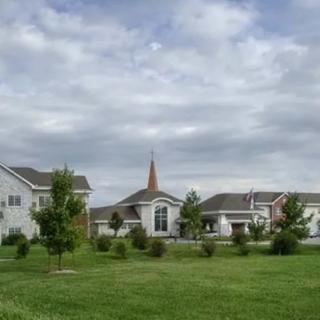 A quaint community church surrounded by greenery under a cloudy sky.