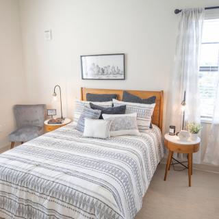 A cozy and modern bedroom with Scandinavian-style decor, featuring a neatly made bed, elegant bedding, and abundant natural light.