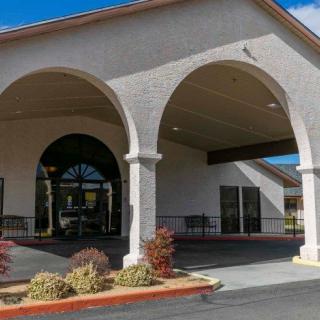 A building entrance featuring arches and a landscaped parking area.