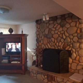 A cozy living room featuring a stone fireplace and an entertainment center with a television.