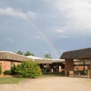 A rainbow arches over a building under a cloudy sky.
