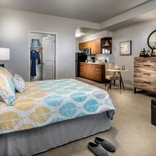 A cozy studio apartment with a comfortable bed, small kitchenette, and stylish decor.