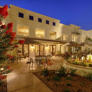 A beautifully lit luxury house with a spacious outdoor patio and garden at night.