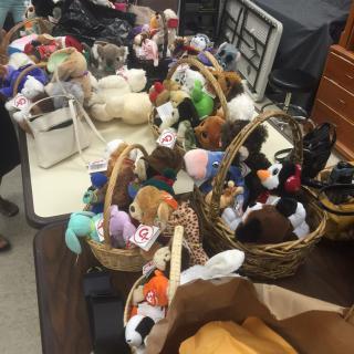 A collection of stuffed animals organized in baskets on a table.