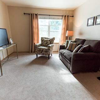 A cozy living room with a sofa, armchair, and television.