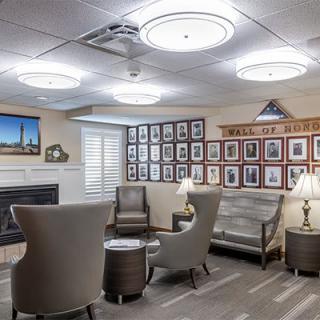 A cozy seating area with modern chairs and a sofa, surrounded by wall photographs and illuminated by ceiling lights.