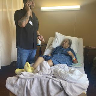 A caregiver on a phone call while attending to a patient in a hospital setting.