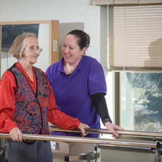 A physical therapist assists an elderly woman during a rehabilitation session.