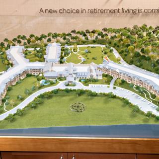 An architectural model showcasing a new retirement living community with landscaped grounds.