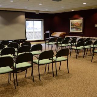 An empty conference room set up with chairs facing a projector screen.