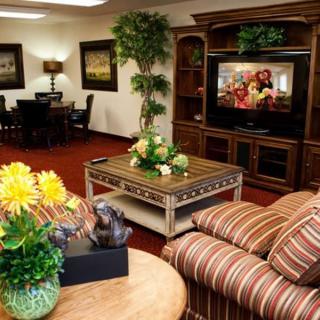 A cozy living room with a striped sofa, wooden furniture, and a television displaying a show.