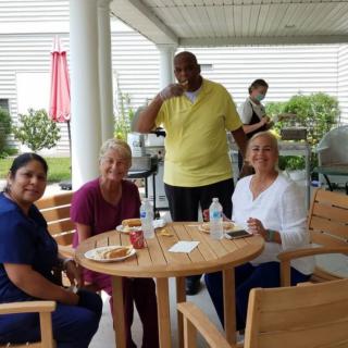 A group of people enjoy a casual outdoor gathering around a table.