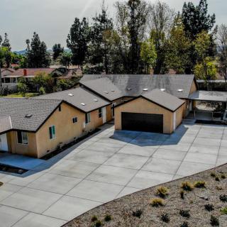 Aerial view of a residential property with a spacious driveway and garage surrounded by trees.