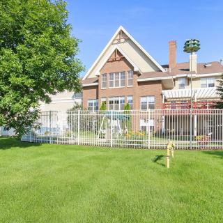 A spacious backyard with a green lawn and a brick house on a sunny day.