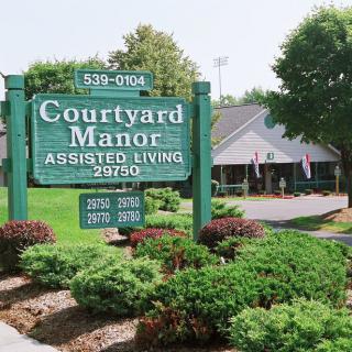 Courtyard Manor Assisted Living facility with well-maintained landscaping and visible signage.