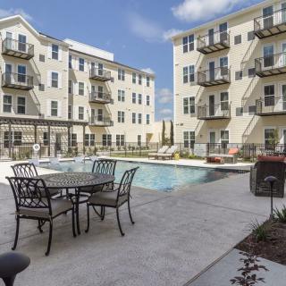 An outdoor view of an apartment complex featuring a swimming pool and patio furniture.