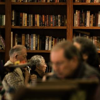 People reading in a cozy library with bookshelves in the background.