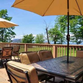 A scenic outdoor patio with seating and umbrellas, overlooking a lush landscape.