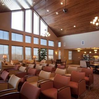 A spacious waiting room with large windows, a wood-paneled ceiling, and comfortable seating arrangements.
