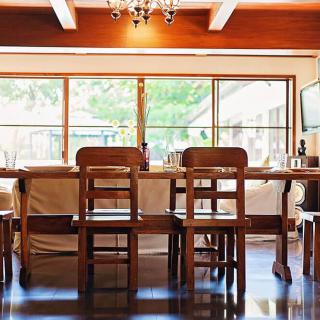 A bright dining area featuring wooden chairs and table with large windows allowing natural light in.