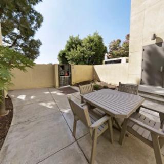 A sunny outdoor patio with a table and chairs surrounded by trees.