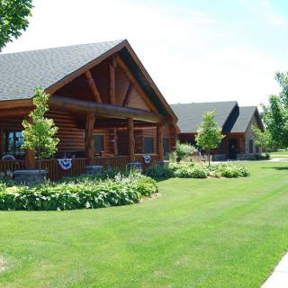 A row of log cabins surrounded by well-maintained lawns and greenery.