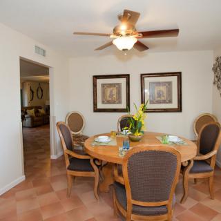 A cozy dining room with a round table, elegant chairs, and wall artwork.