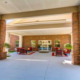 A covered entrance to a building with outdoor seating and potted plants.