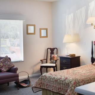 Cozy bedroom with a bed, chairs, and a window.