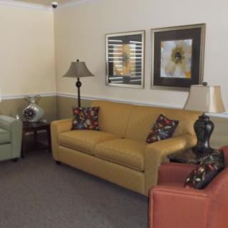 A cozy living room featuring a yellow sofa, an armchair, and decorative lamps with floral artwork on the walls.