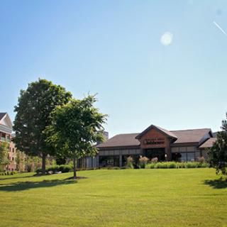 A serene outdoor view featuring a well-maintained building surrounded by lush greenery and a clear blue sky.