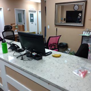 A view of a modern reception area with a desk, computer, and seating.