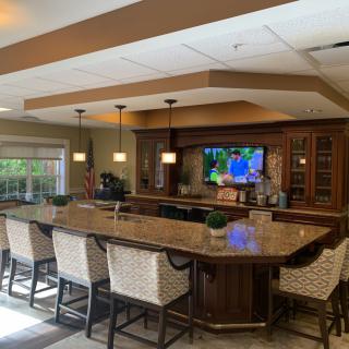 A cozy indoor bar with a long counter, wicker chairs, and a television on the wall.