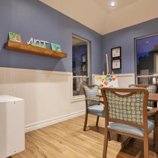 A stylish dining room with blue walls, modern wooden furniture, and decorative artwork creating a cozy atmosphere.