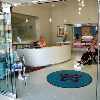 A welcoming reception area in a healthcare facility, featuring a front desk and seating for visitors, including accommodations for those using wheelchairs.