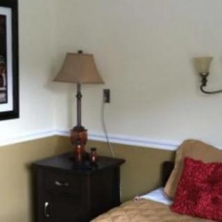 A cozy bedroom corner with a lamp on a nightstand beside a bed.