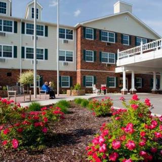 A landscaped garden with blooming flowers in front of a multi-story brick and white building.