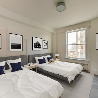 A modern bedroom with two twin beds, featuring neutral tones and artistic decor.