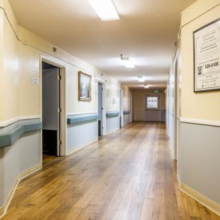 A well-lit hallway with wooden flooring and adorned walls.