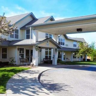 A residential building with a driveway and landscaped surroundings on a sunny day.