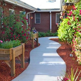 A beautifully landscaped garden with a winding pathway and vibrant flowers in raised beds.