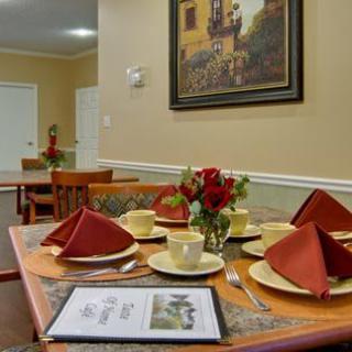 A neatly set dining table with decorative napkins and a floral centerpiece in a cozy room.