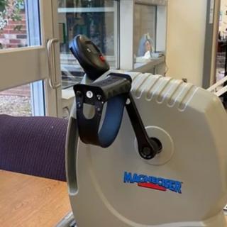 A hand-operated exercise bike on a table indoors.