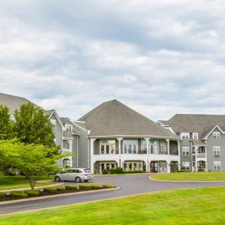 A large residential building surrounded by greenery under a cloudy sky.