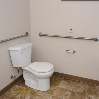An accessible bathroom featuring a toilet with grab bars for support.