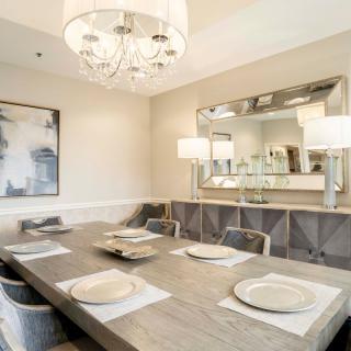 A modern dining room featuring a chandelier, with elegant table settings and contemporary artwork on the wall.