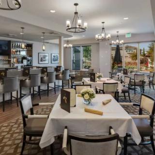 A stylish and modern restaurant interior with neatly arranged tables and chairs, illuminated by elegant chandeliers.