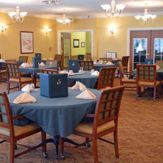 An elegantly set dining room with multiple round tables and chairs, featuring a warm interior design.